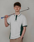 Person wearing a white and green polo shirt holding a golf club against a plain background