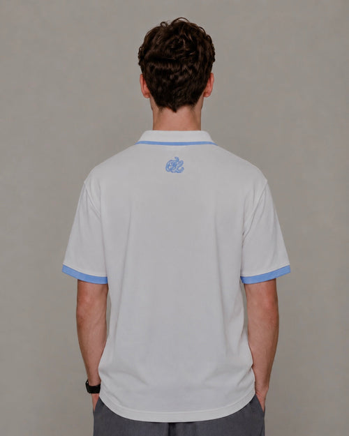 Person wearing a light gray polo shirt with blue trim on a plain background