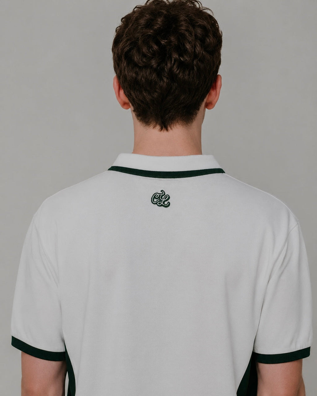 Person wearing a white polo shirt with black trim on a plain background