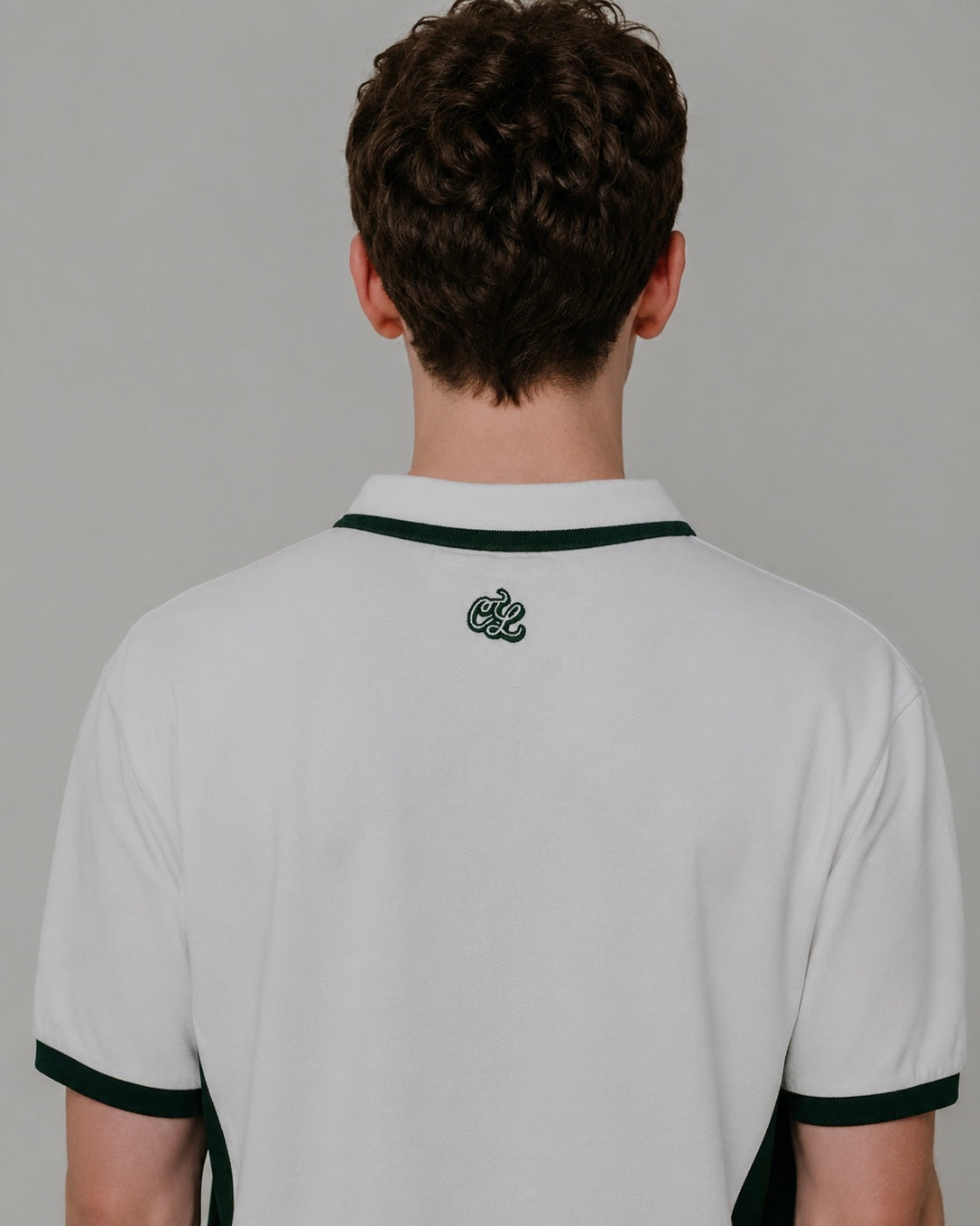 Person wearing a white polo shirt with black trim on a plain background