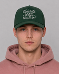 Person wearing a green cap with 'Concrete Links' text and a pink hoodie against a gray background