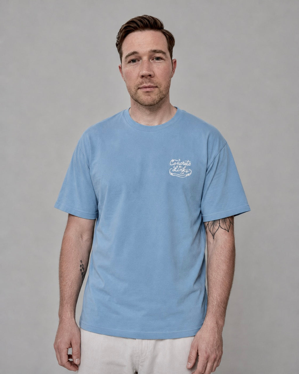 Man wearing a light blue t-shirt with a logo on a gray background