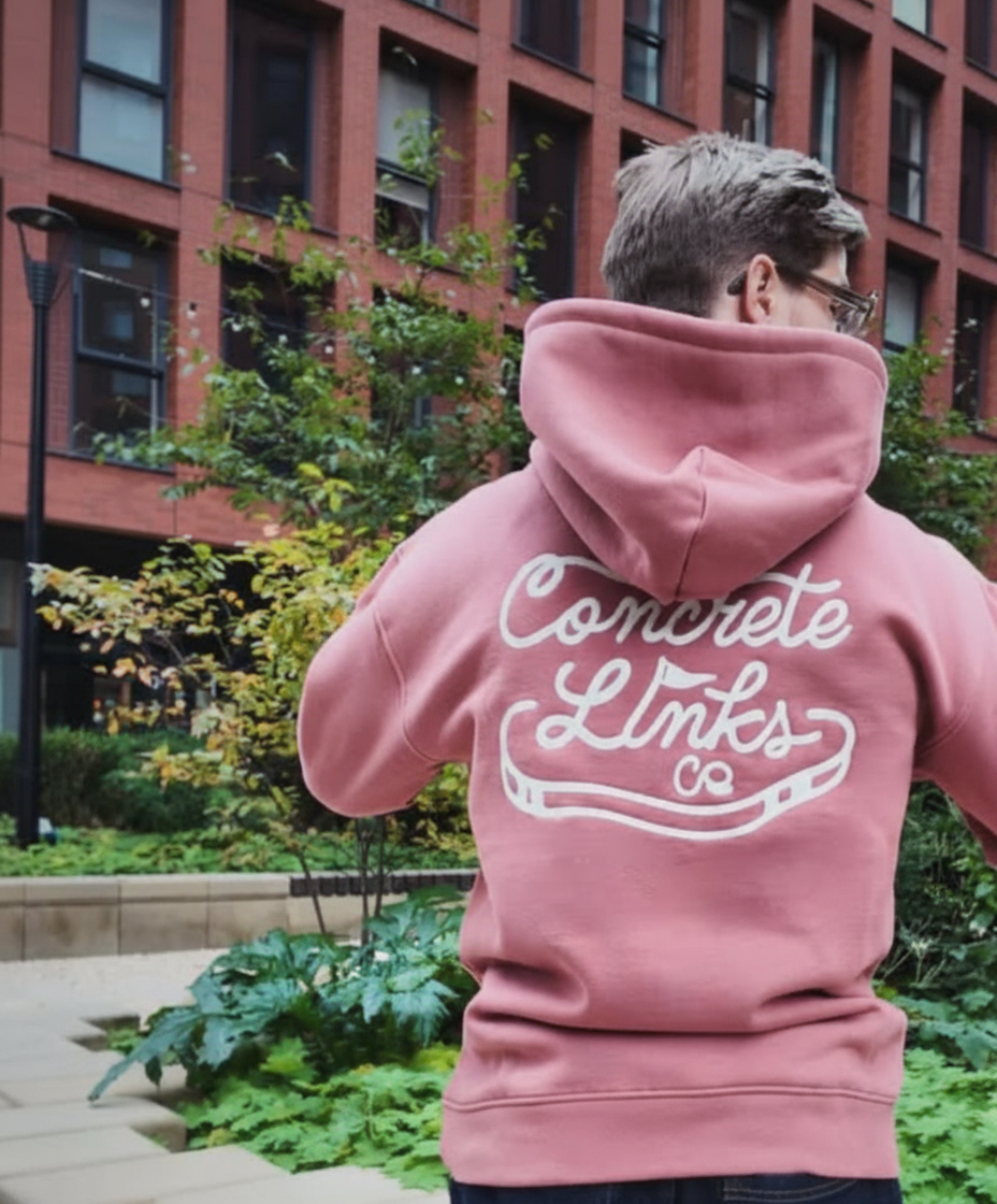 Person wearing a pink hoodie with 'Concrete Links' text in an urban setting