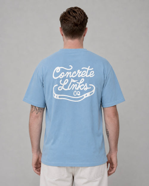 Man wearing a light blue t-shirt with 'Concrete Links' logo on the back against a gray background